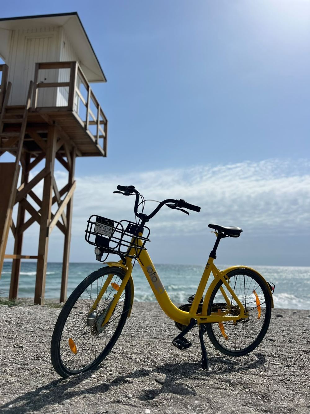 Bicicleta amarilla de alquiler junto a una torre de socorrista frente al mar